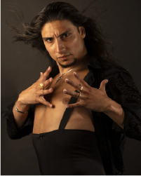 Two women in black tops and grey skirts dancing together with a long braid between them connecting each to the other. They lean away from one another.