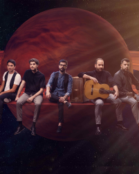 Two women in black tops and grey skirts dancing together with a long braid between them connecting each to the other. They lean away from one another.